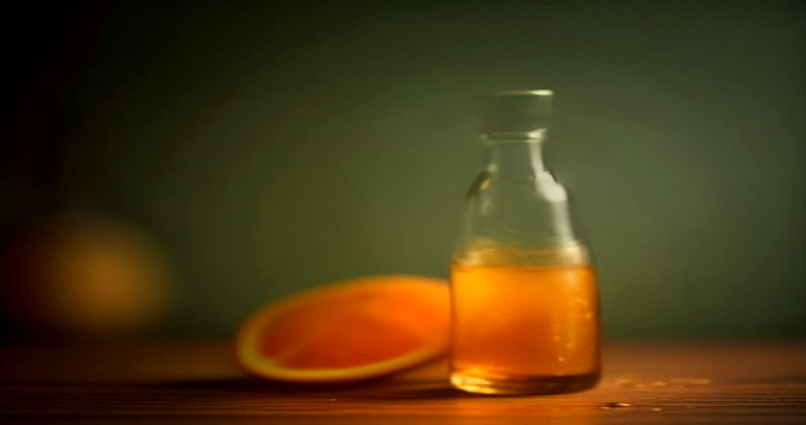 Amber spirits and a slice of orange on a dark wooden counter